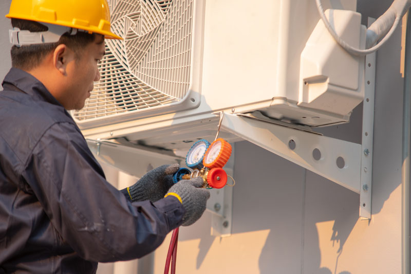 Technician use measuring equipment for filling air conditioners.