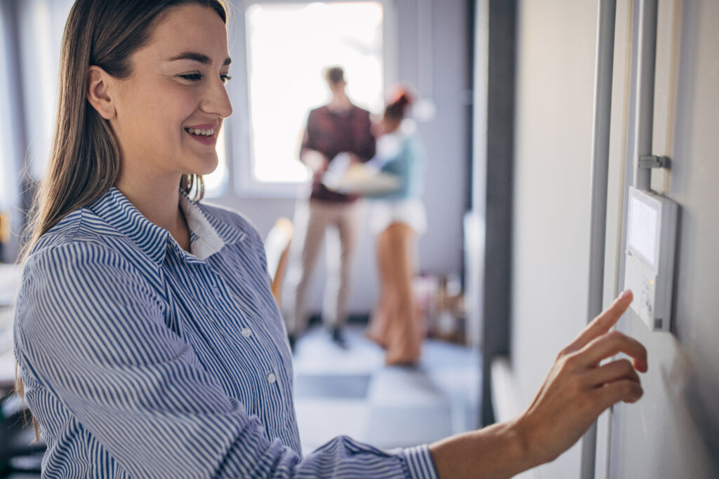 Woman changing the temperature on a thermostat.