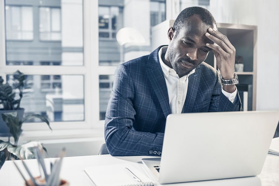 How to Reduce Your Company’s Energy Costs. Image shows man sitting at a desk and looking at his laptop.