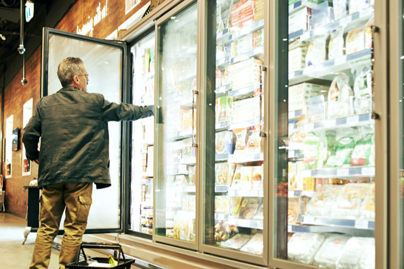 Commercial Refrigerator Repairs Oak Brook, IL. Photo of a customer in a grocery store or gas station reaching into a cooler for a product.